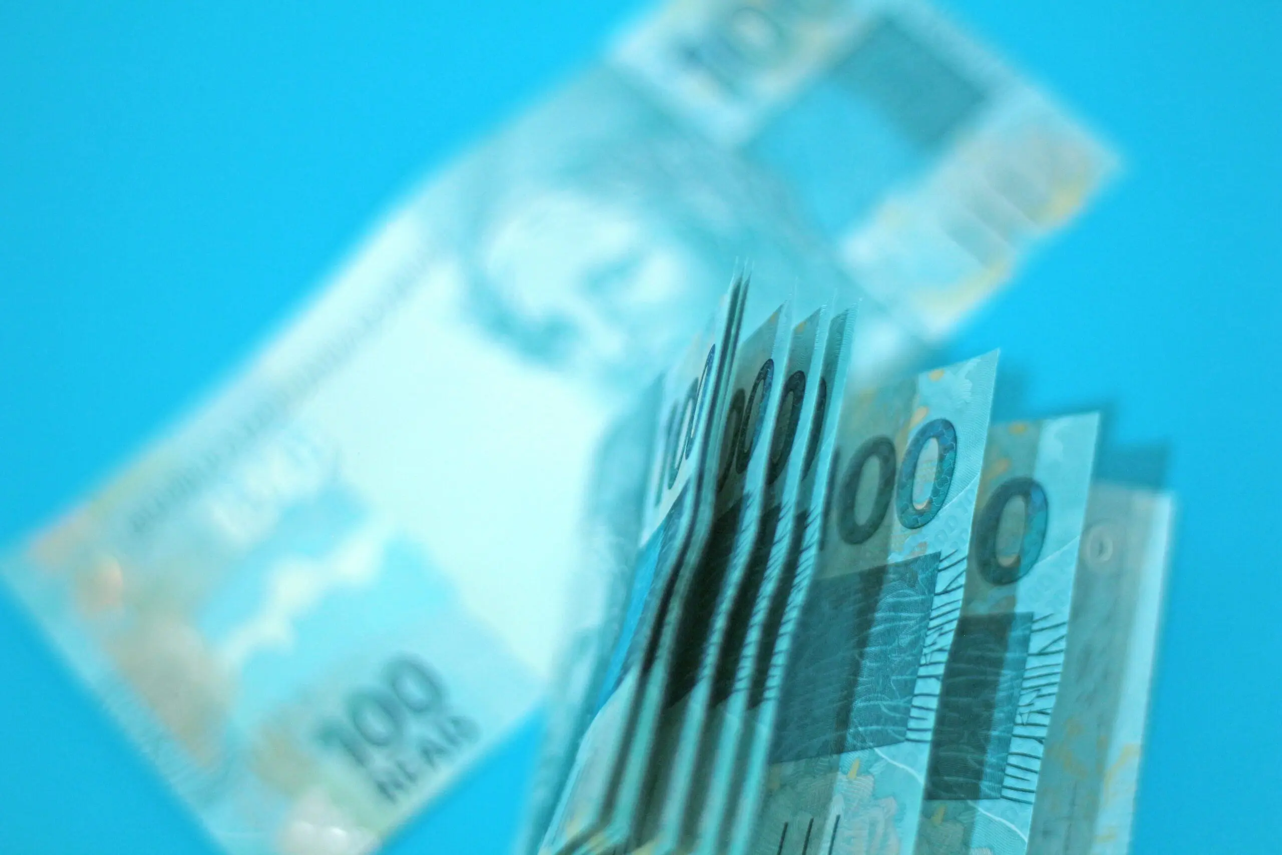 Notas de cem reais em um fundo azul.