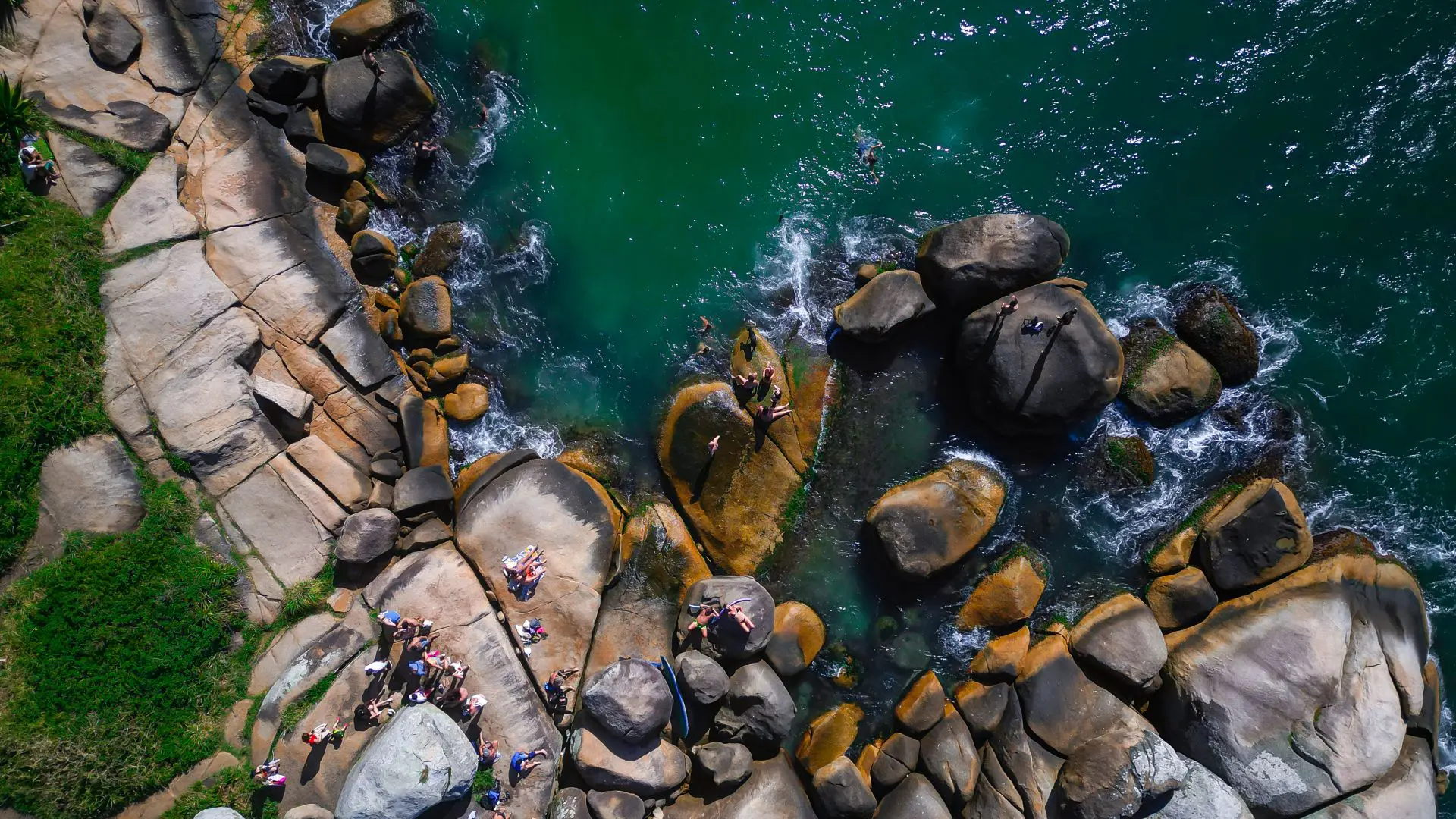Piscinas Naturais da Barra da Lagoa, em Florianópolis, destino acessível por trilha que leva a um cenário de águas cristalinas entre as pedras.
