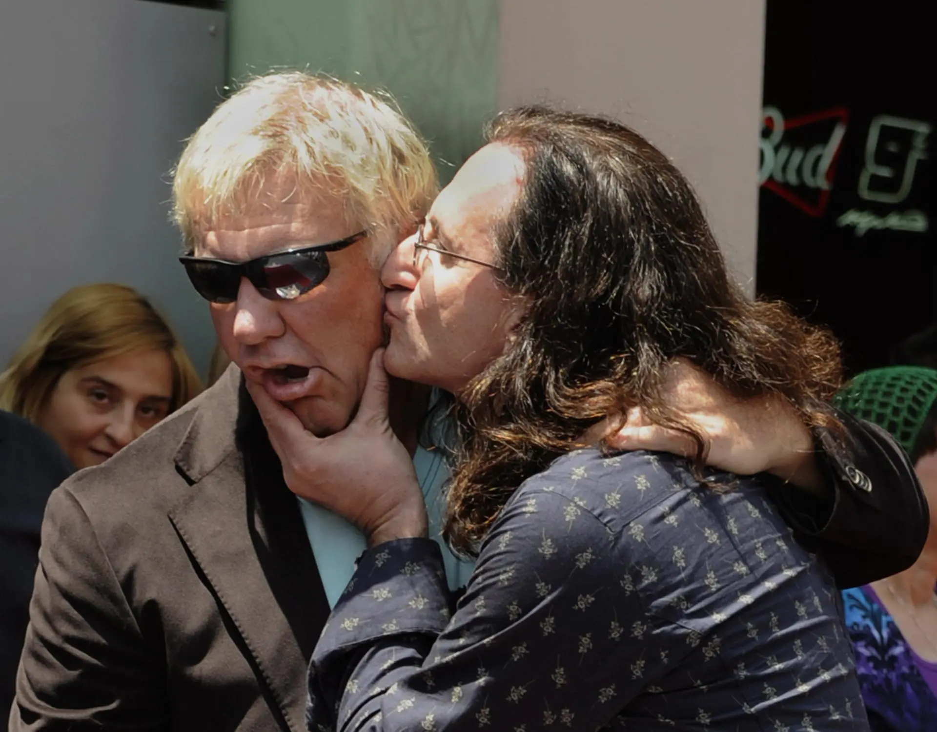 O serelepe Geddy Lee tasca um beijo na bochecha de Alex Lifeson