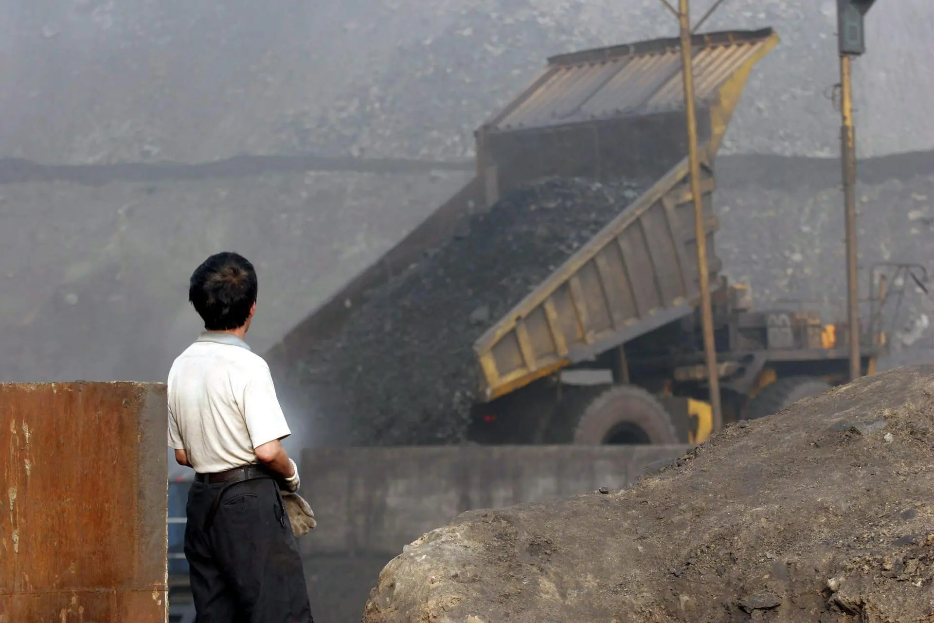 Foto de arquivo datada de 7 de julho de 2005, mostra um trabalhador observando uma grande escavadeira despejando carvão em uma vala de coleta na mina de carvão a céu aberto de Antaibao, perto de Shuozhou, província de Shanxi, China.