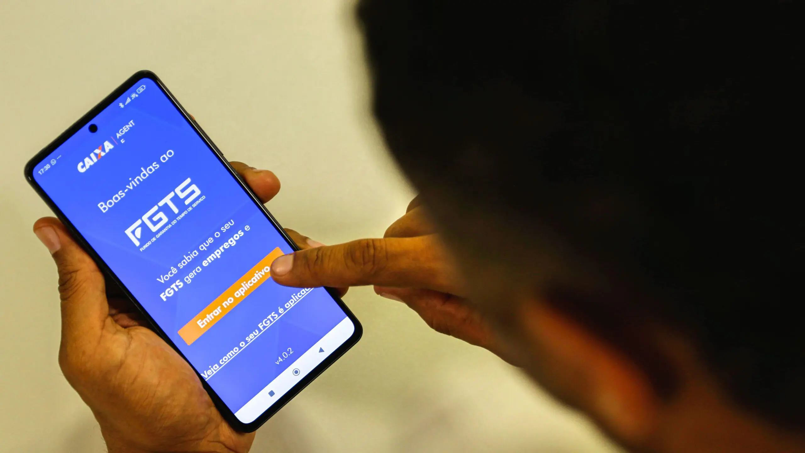 Trabalhador consulta o saldo do saque FGTS e as regras do saque-aniversário pelo aplicativo no celular.