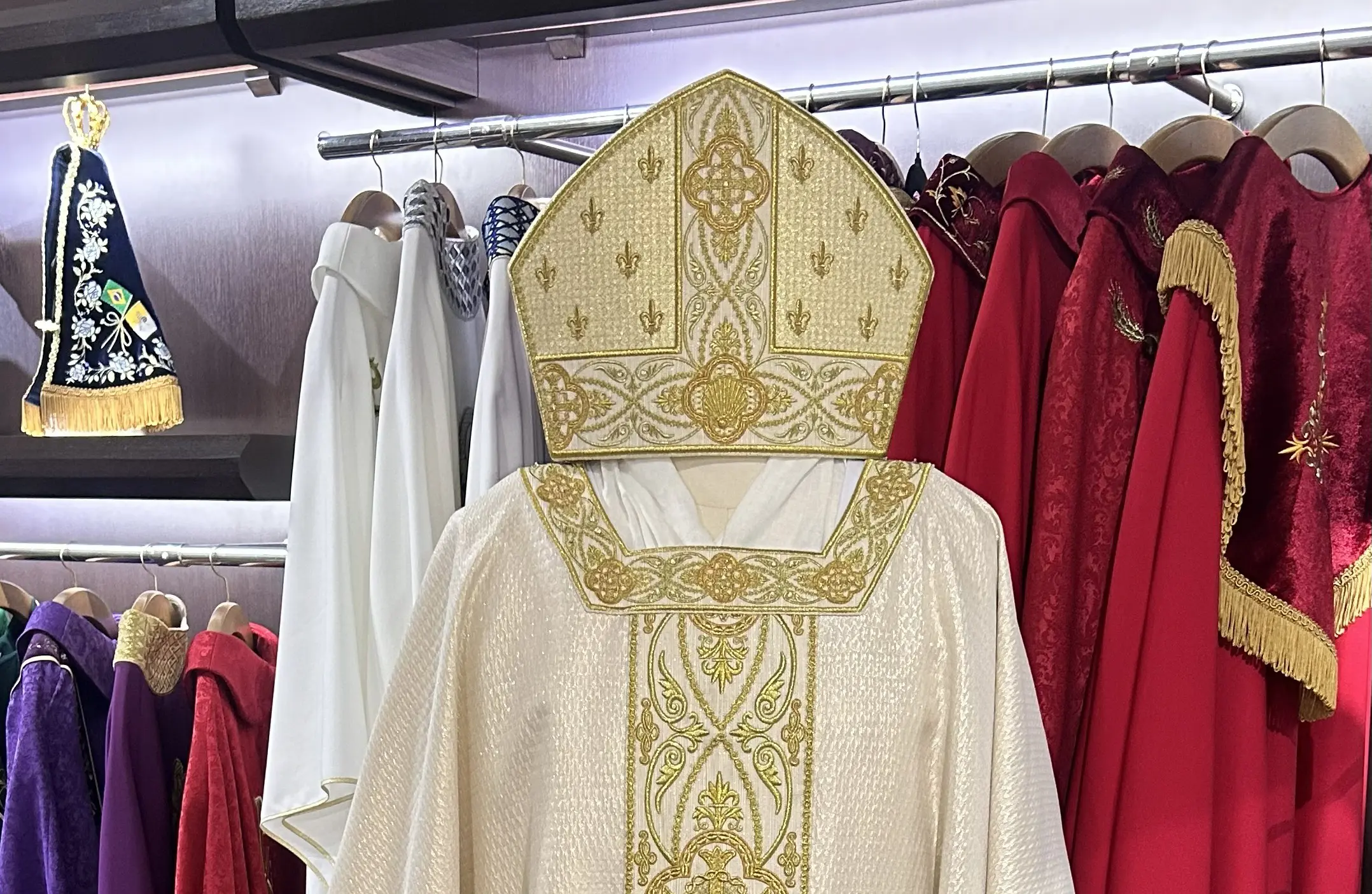 Paramentos moldados em tecidos nobres ganham cruzes, flor-de-lis e linhas de contas que evocam o rosário, criando a identidade visual das celebrações papais.