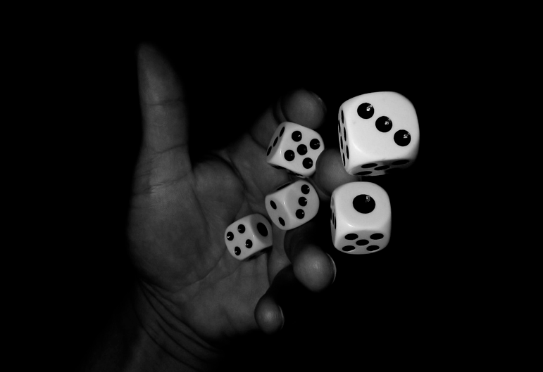 Uma mão jogando dados, assim como as apostas dependem da sorte, são sempre imprevisíveis