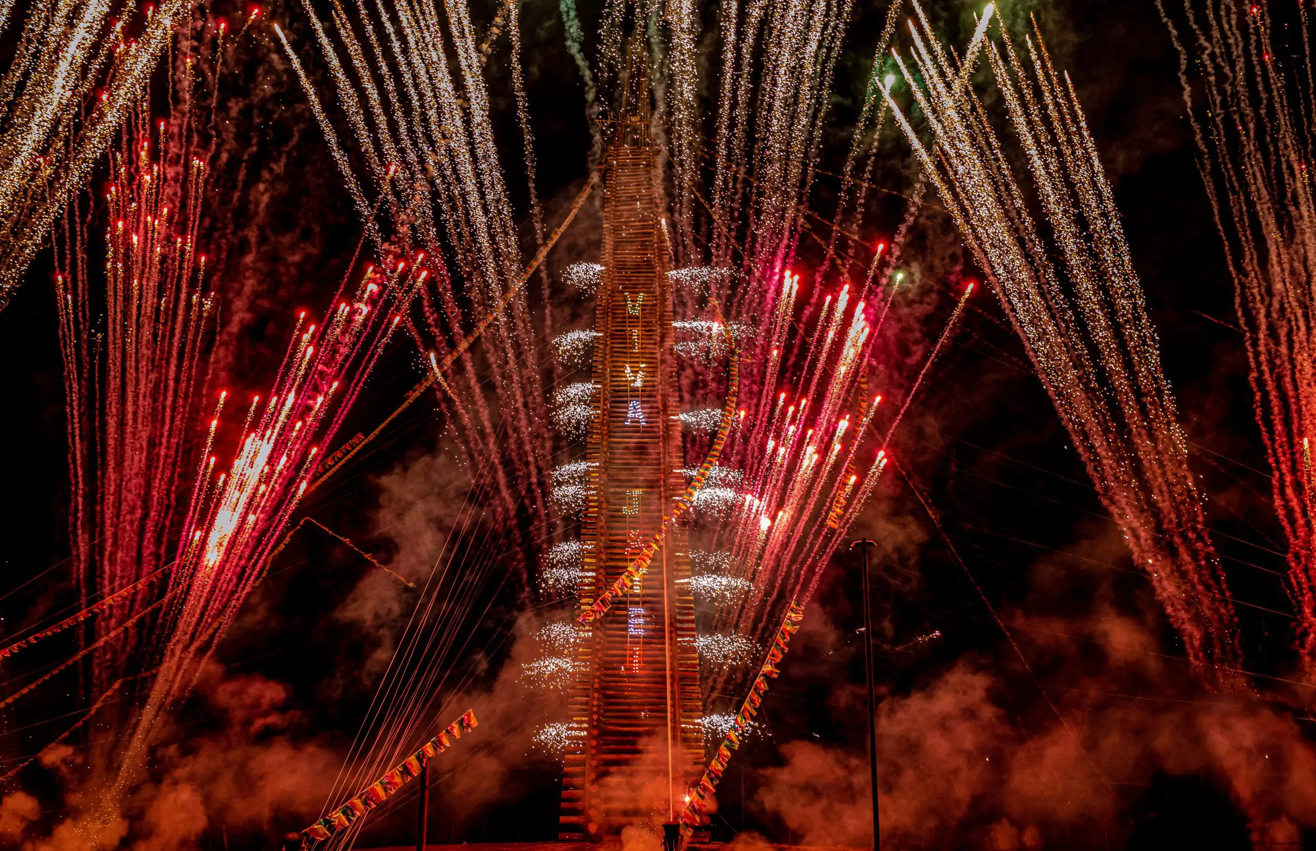 O que começou em 1946 com uma pequena imagem e um terço rezado em família, hoje alcança os 60 metros de altura. A fogueira de Jateí (MS), que já figurou no Guinness, leva um mês para ser montada com madeira de reflorestamento e estrutura hidráulica.