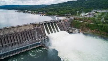 Usina hidrelétrica em operação, com vertedouro aberto e liberação de água, evidenciando a força da geração hídrica como base da energia firme no sistema elétrico brasileiro.