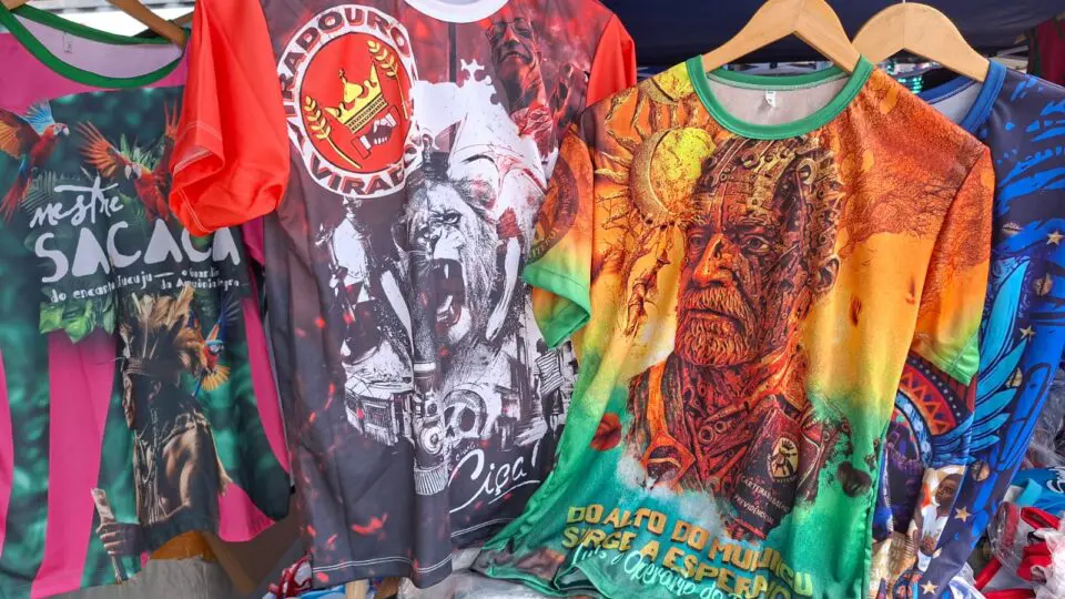 Lula é retradado com rosto de engrenagens em camiseta (à dir.) da escola de samba Acadêmicos de Niterói