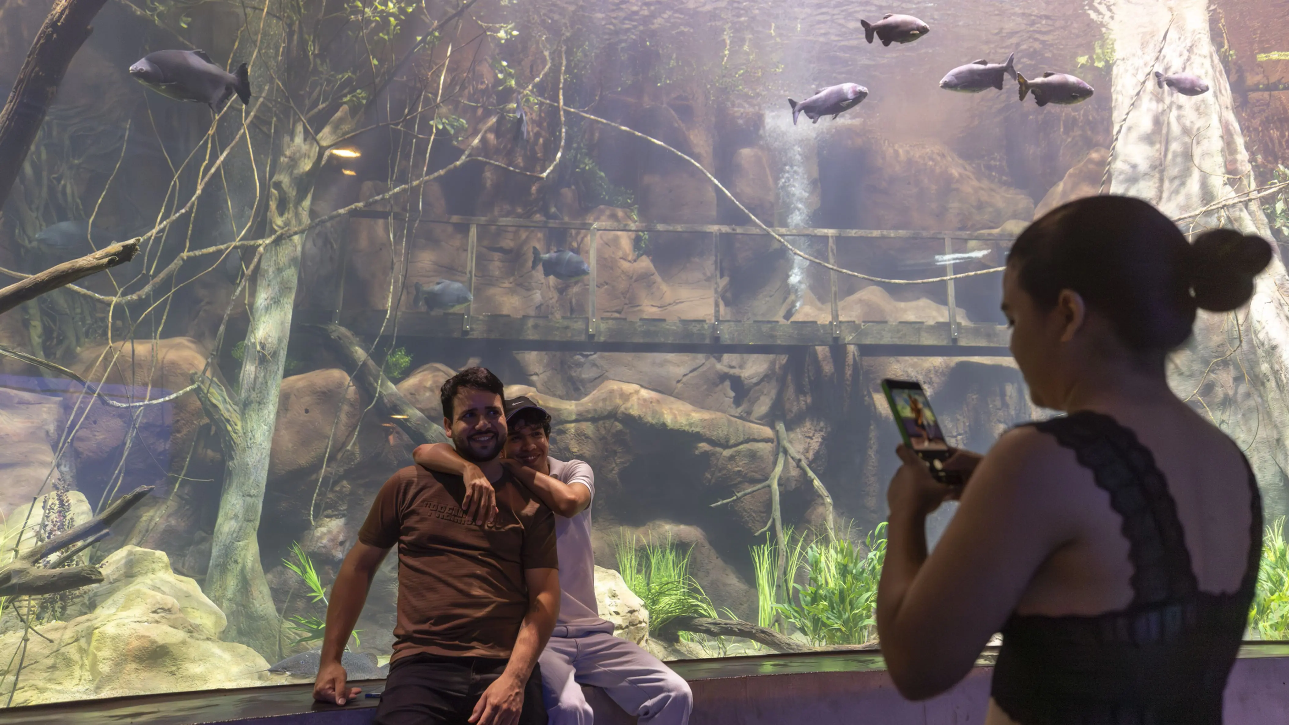 Visitantes registram momento diante de um dos grandes tanques do AquaFoz, que apresenta espécies dos rios da região em ambiente imersivo.