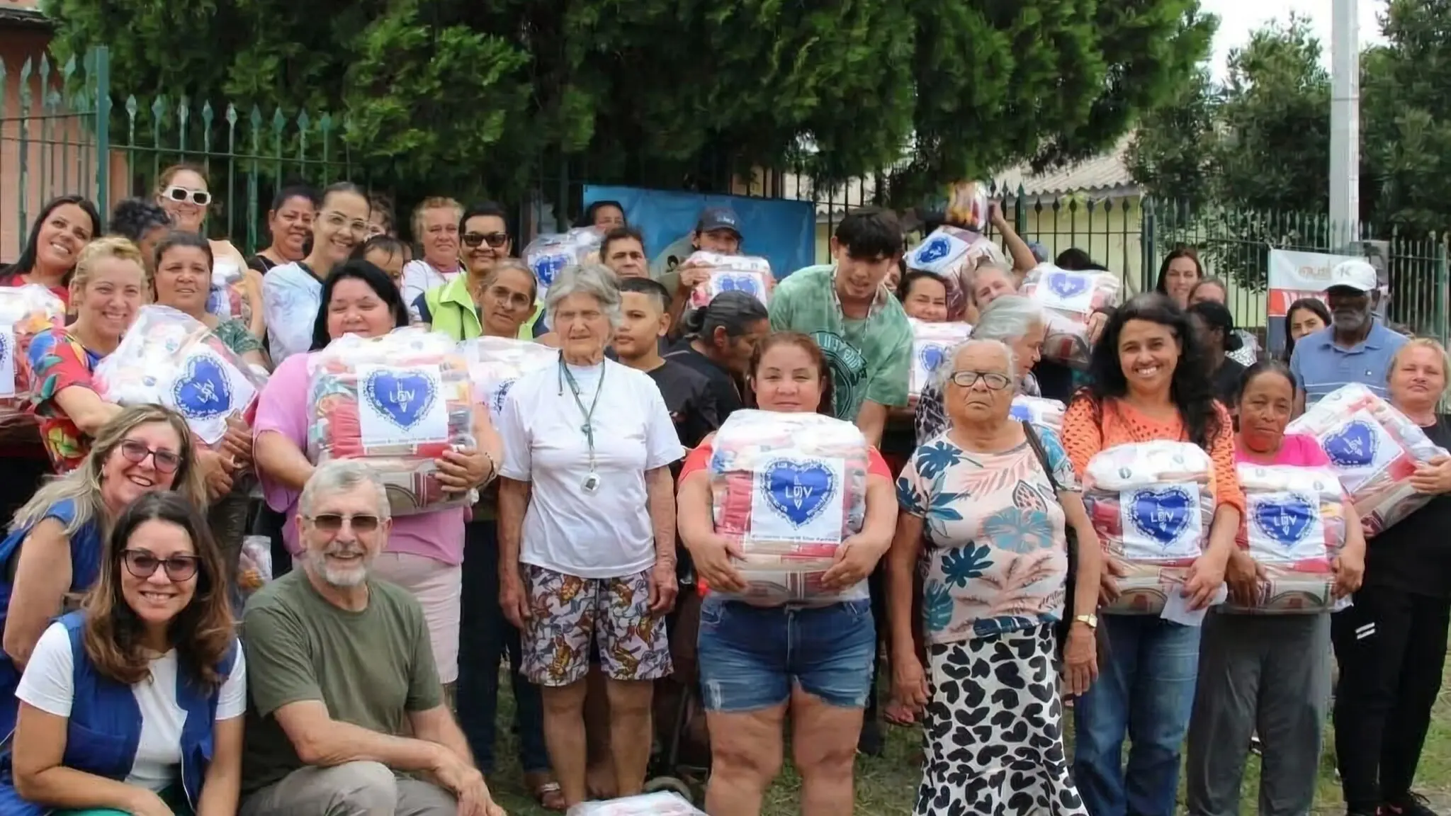 A imagem mostra várias pessoas reunidas em um evento de solidariedade