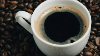 Xícara de café com grãos ao lado, que pode melhorar o humor.