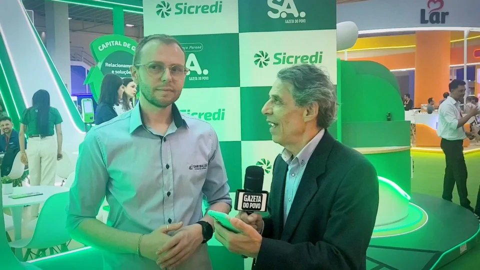 O jornalista Celio Martins entrevista André Rech, gestor de comunicação da Cooperativa Vinícola Garibaldi, durante a Expoapras 2026, sobre expansão no Paraná, consumo de vinhos e crescimento dos espumantes.