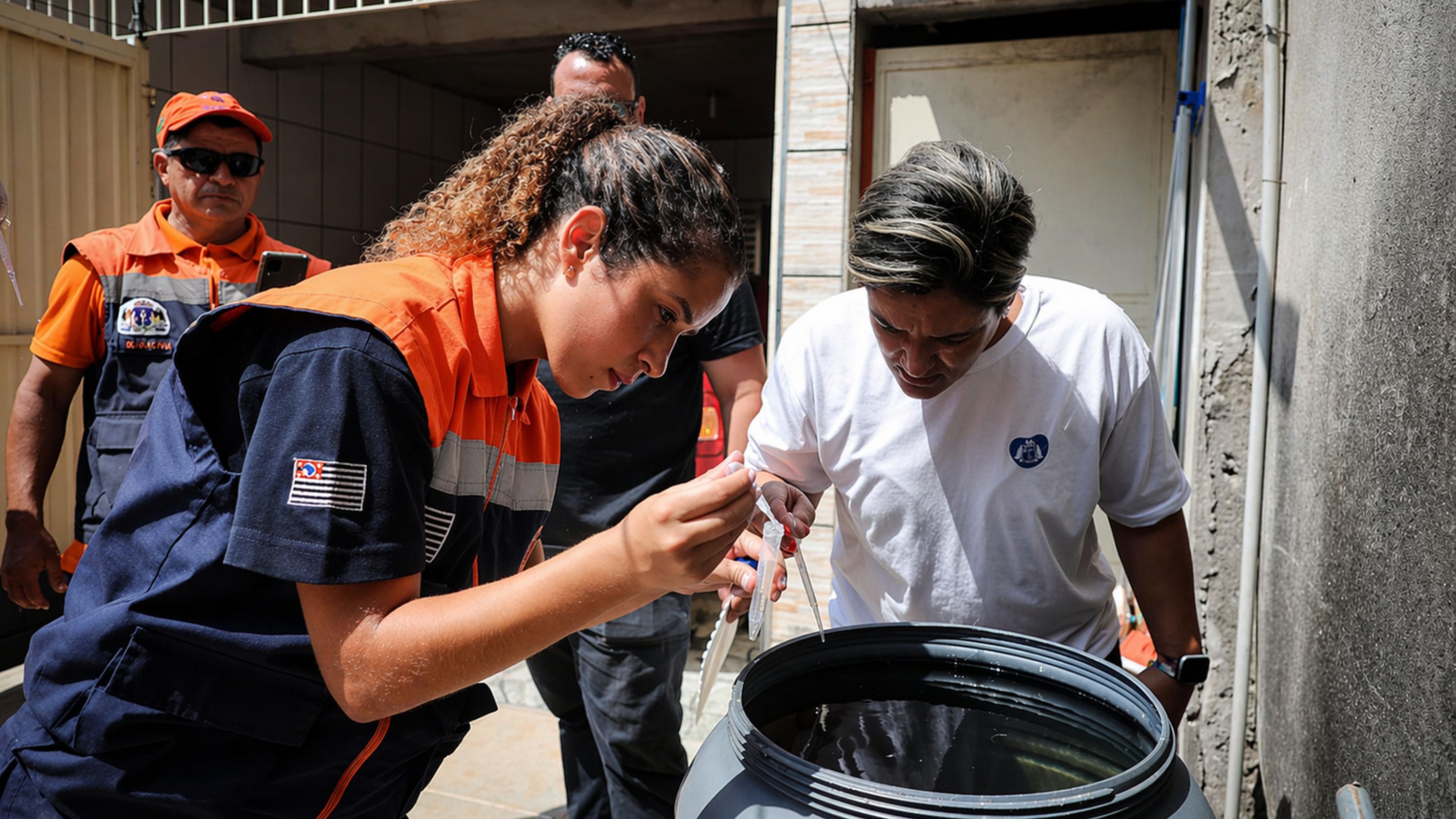 Agentes vistoriam reservatório doméstico em ação de combate à dengue, reforçando a importância da prevenção dentro de casa.