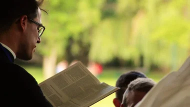 Imagem mostra um padre lendo um trecho da Bíblia Sagrada.