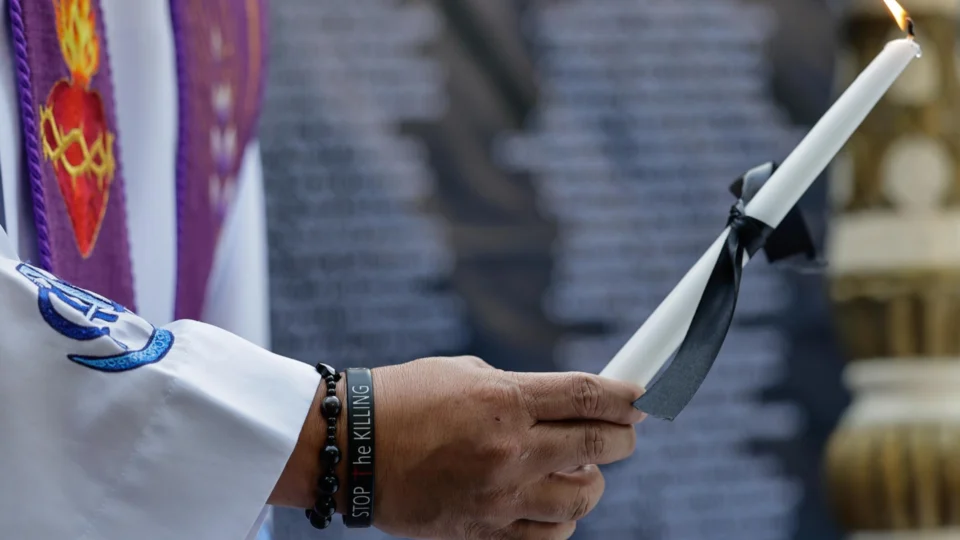 Padre católico segura uma vela