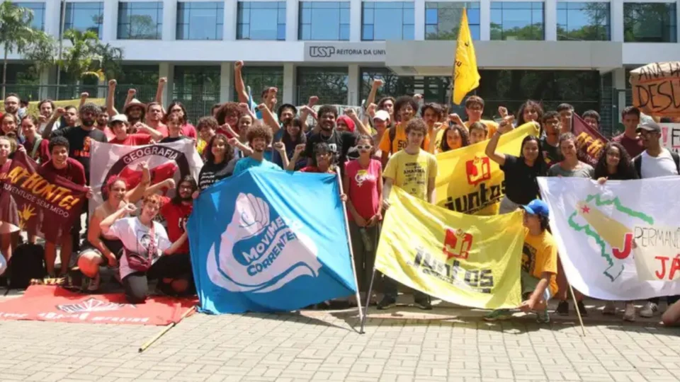 Integrantes do Correnteza, segurando a bandeira azul do movimento, durante um protesto na USP em 2023: grupo se diferencia por ocupar espaços públicos e adotar uma estratégia de agitação permanente