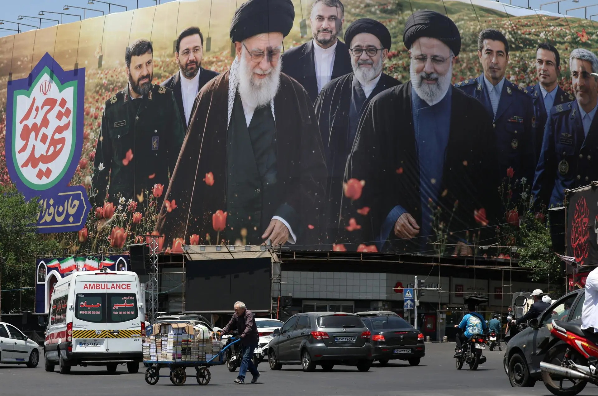 Trabalhador passa diante de outdoor com imagens de Ali Khamenei e Ebrahim Raisi, na praça Enghelab, em Teerã, em meio à continuidade das tensões entre Irã e Estados Unidos.