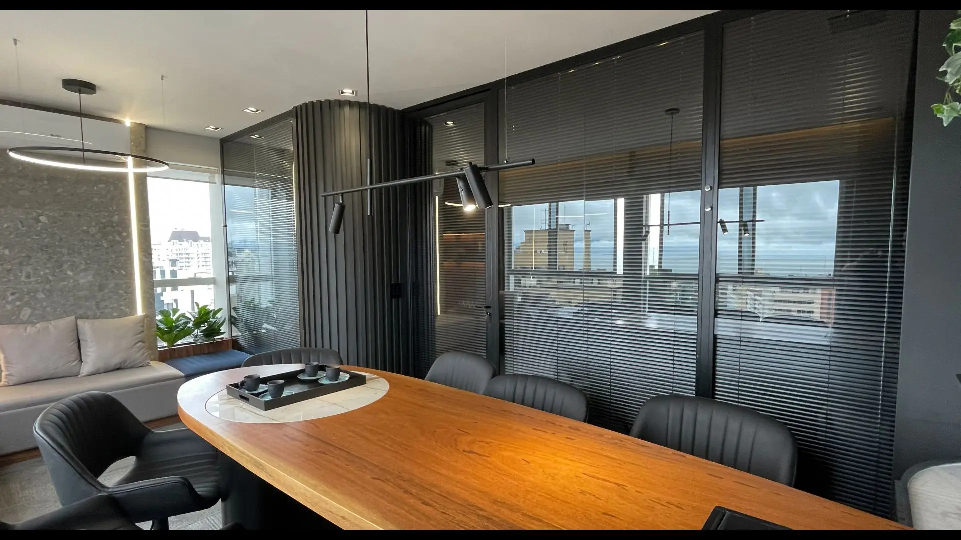 Sala de reuniões com divisórias de vidro e persianas integradas combina privacidade, sofisticação e design para ambientes corporativos de alto padrão.