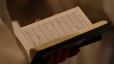 Pessoa segurando partitura de canto gregoriano.