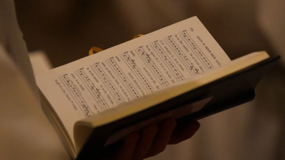 Pessoa segurando partitura de canto gregoriano.