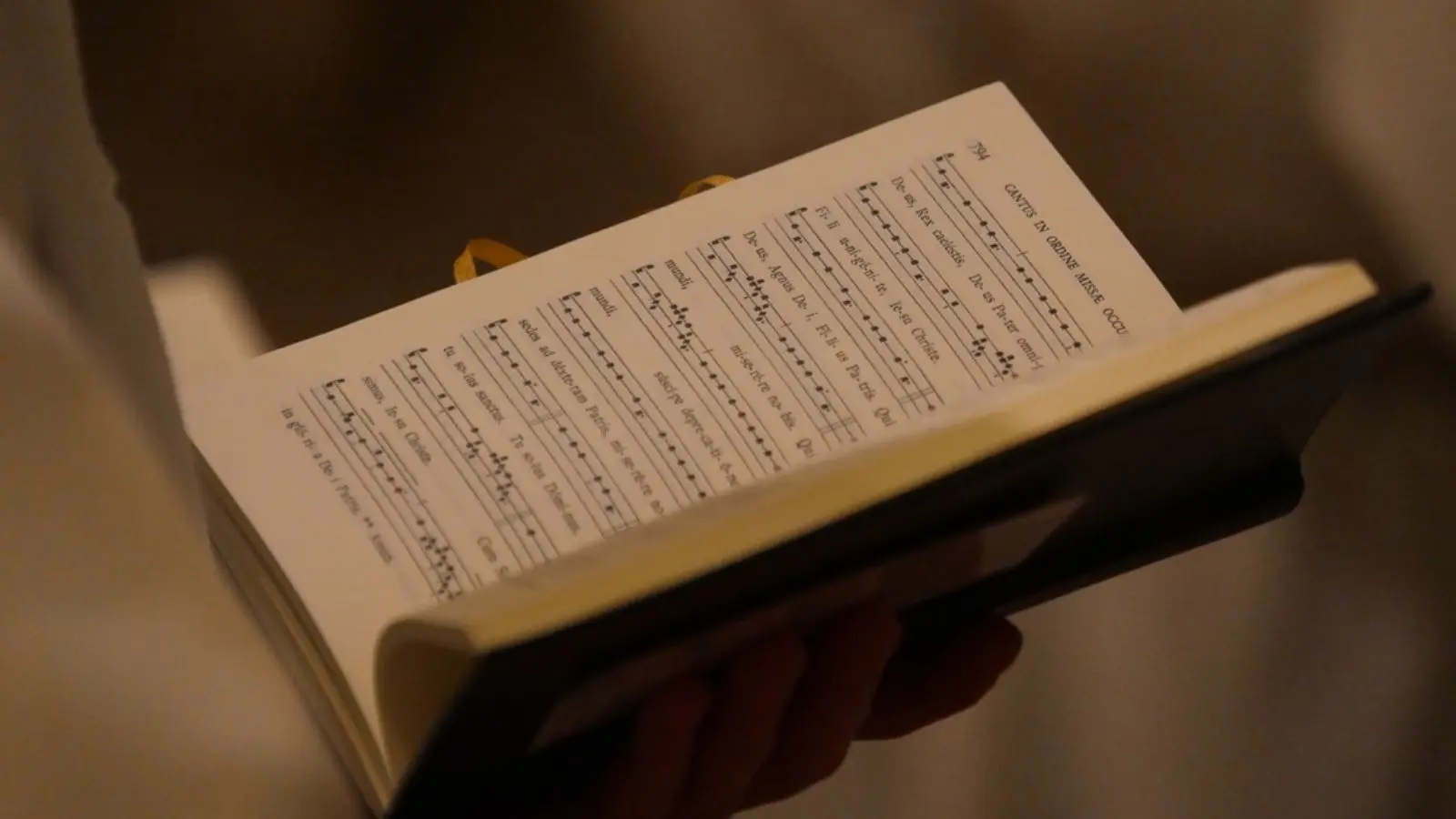 Pessoa segurando partitura de canto gregoriano.