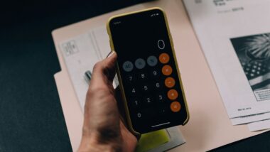 Pessoa com calculadora na mão calculando as taxas da Reforma Tributária.