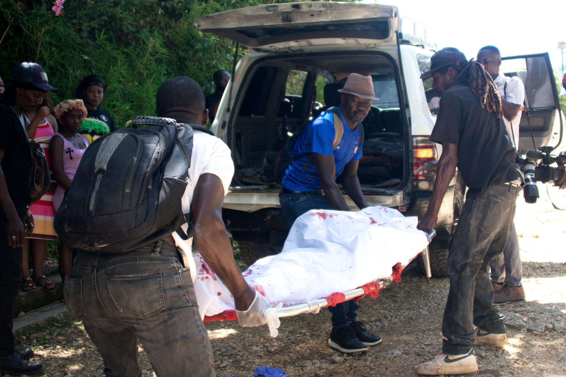 Pessoas retirando o corpo de uma vítima após o ataque de gangues armadas em Kenscoff, nos arredores de Porto Príncipe, no Haiti, nesta segunda-feira (24)