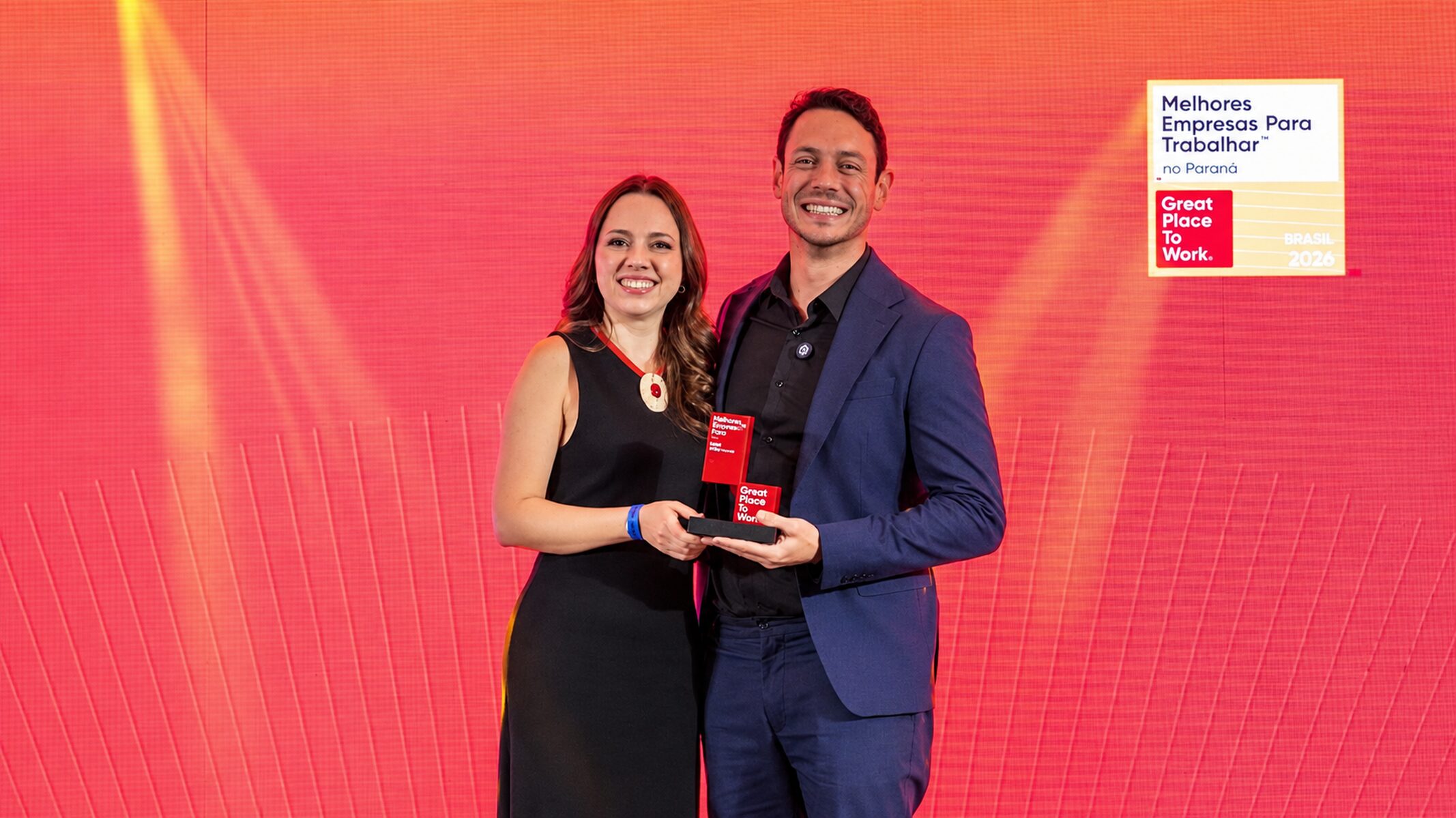 Renan Kaminski, CMO e sócio-cofundador, e Juliana, Head de RH da 4blue, sobem ao palco para receber o reconhecimento da empresa no 13º lugar - GPTW Paraná 2026.