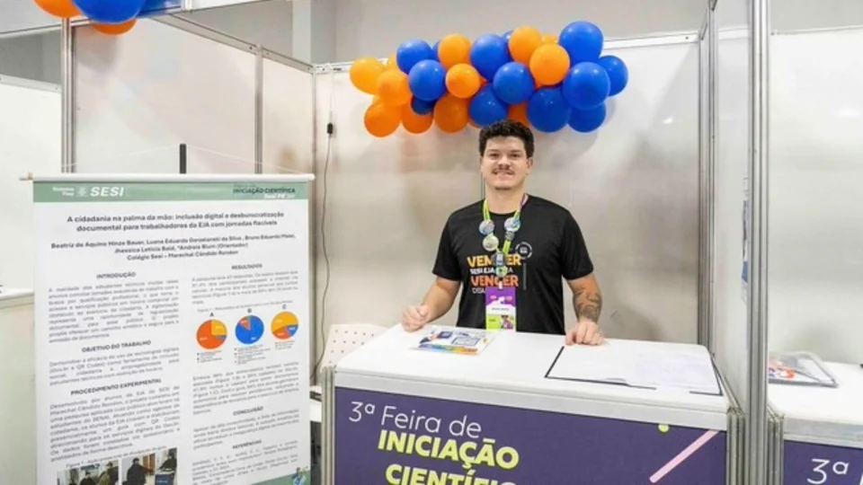 Foto do estudante na bancada de apresentação na Feira de Iniciação Científica do Sesi.