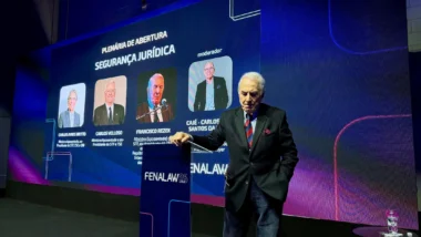 Ex-ministro Francisco Rezek apoiado no púlpito da Fenalaw durante debate sobre decisões monocráticas no STF, com telão ao fundo que mostra os participantes da plenária de abertura.