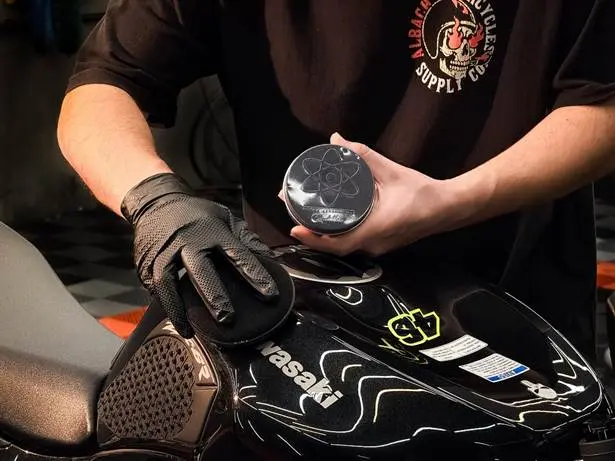 Aplicação de cera Cadillac no cuidado e acabamento da pintura de uma motocicleta.