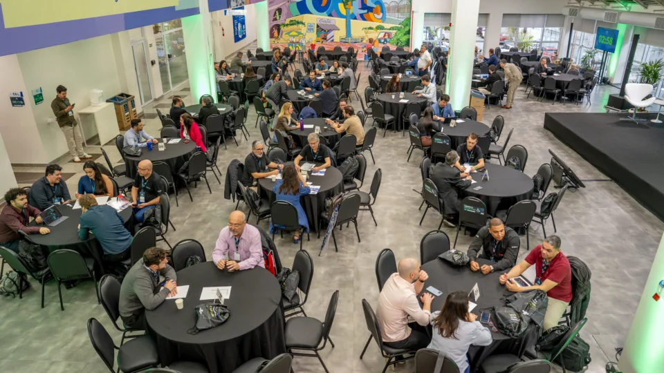 Mesas de reunião com empresários conversando em rodada de negócios de tecnologia