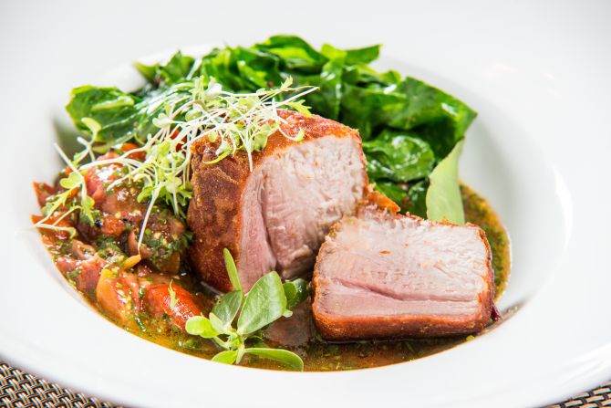 Lombo de leitoa caipira com pururuca de presunto cru, salada de tomatinho cereja e couve rasgada com alho, servida com virado de feijão e arroz. Foto: Divulgação.