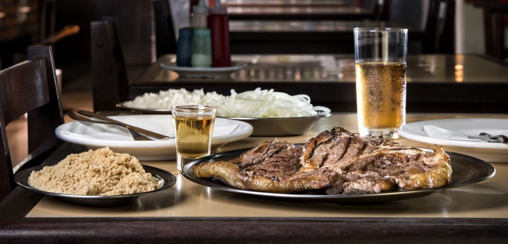 O churrasco paranaense está no cardápio do Bar Palácio há décadas. O t-bone (500 g de filé e contrafilé) vem à mesa acompanhado de arroz, cebola e farofa (R$ 38). Foto: Letícia Akemi/Gazeta do Povo