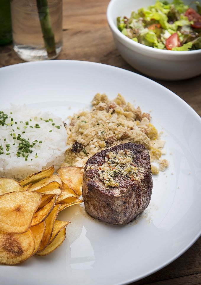 O prato Oswaldo Aranha é composto por filé mignon, arroz branco, farofa de bacon e ovos e chips de batata (R$ 34,50) O prato Oswaldo Aranha é composto por filé mignon, arroz branco, farofa de bacon e ovos e chips de batata (R$ 34,50)