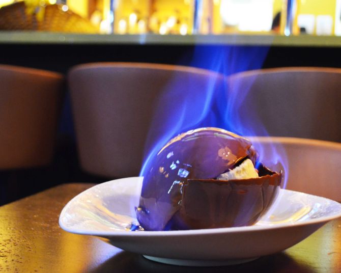 Ice Bomb (R$ 23), casca de chocolate belga em formato de bola recheada com sorvete de creme e calda de morango, flambado à mesa. Foto: Divulgação. Ice Bomb (R$ 23), casca de chocolate belga em formato de bola recheada com sorvete de creme e calda de morango, flambado à mesa. Foto: Divulgação.