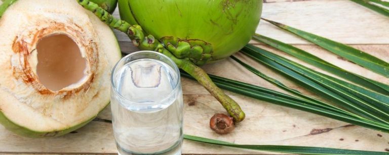 Fresh Coconut Water Drink with coconut leaf on wooden background