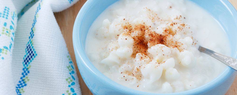 Brazilian dessert canjica of white corn with cinnamon in blue bowl. Selective focus