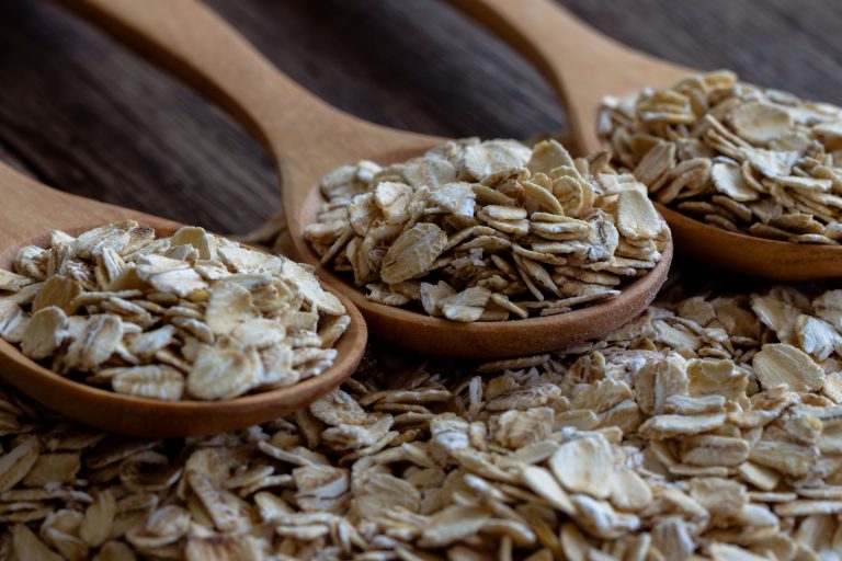 Oat flakes or oatmeal in wood spoon on rustic wood table. Rolled oat is clean food for health lover people. Prepare oat flakes for bakery or cooking.Natural organic food in vintage style concept.Oat flake, oatmeal background and texture.