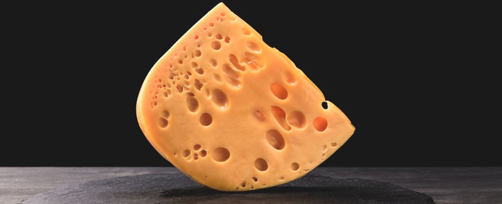 Close up shot of emmental cheese on board on black