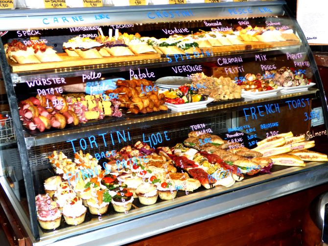 A vitrine do Bacarando in Corte dell'Orso expõe várias opções de cicchetti. Foto: Gillo Brunisso A vitrine do Bacarando in Corte dell'Orso expõe várias opções de cicchetti. Foto: Gillo Brunisso