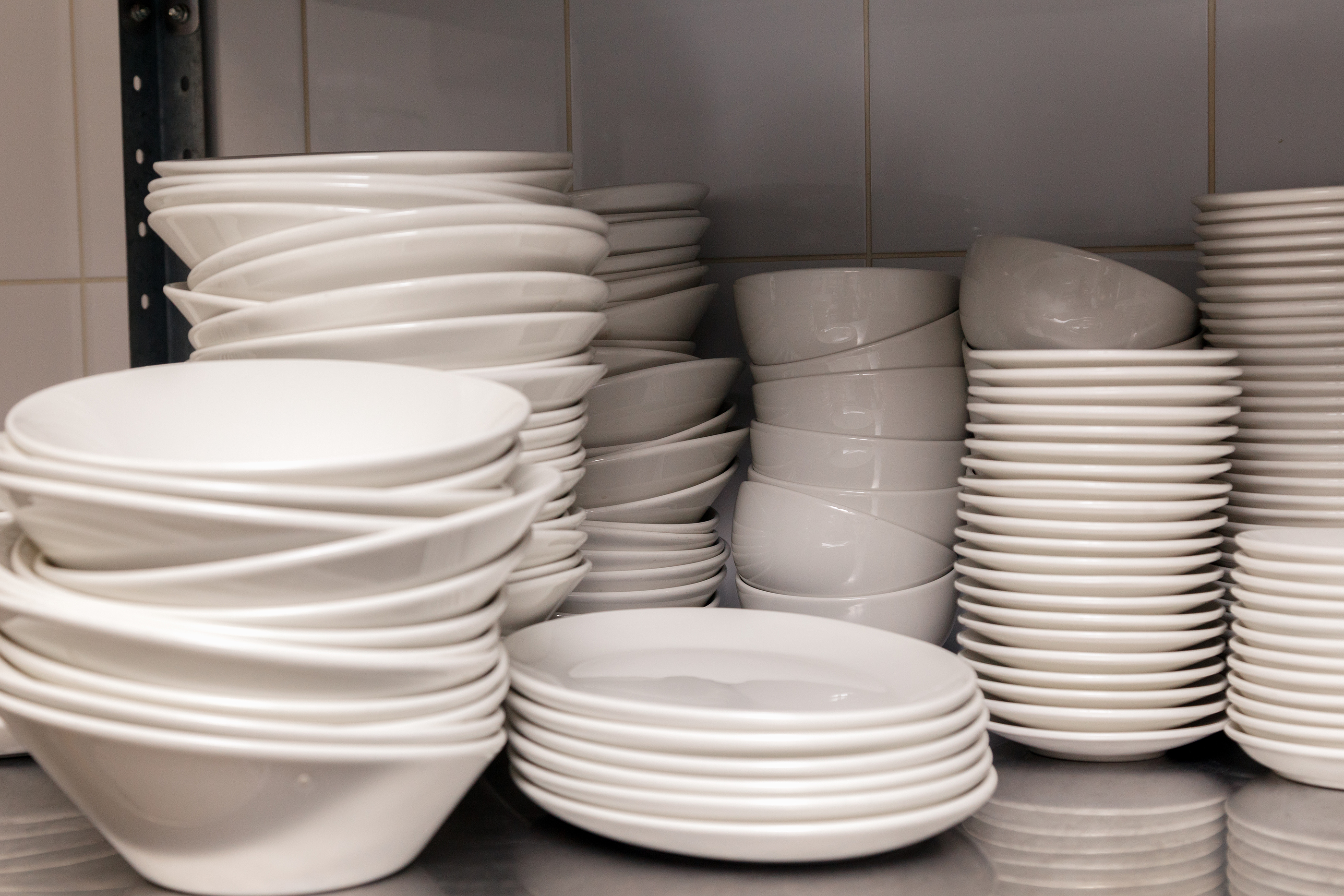 Dirty dishes, wine glasses, plates, cups on a metal rack in the restaurants kitchen