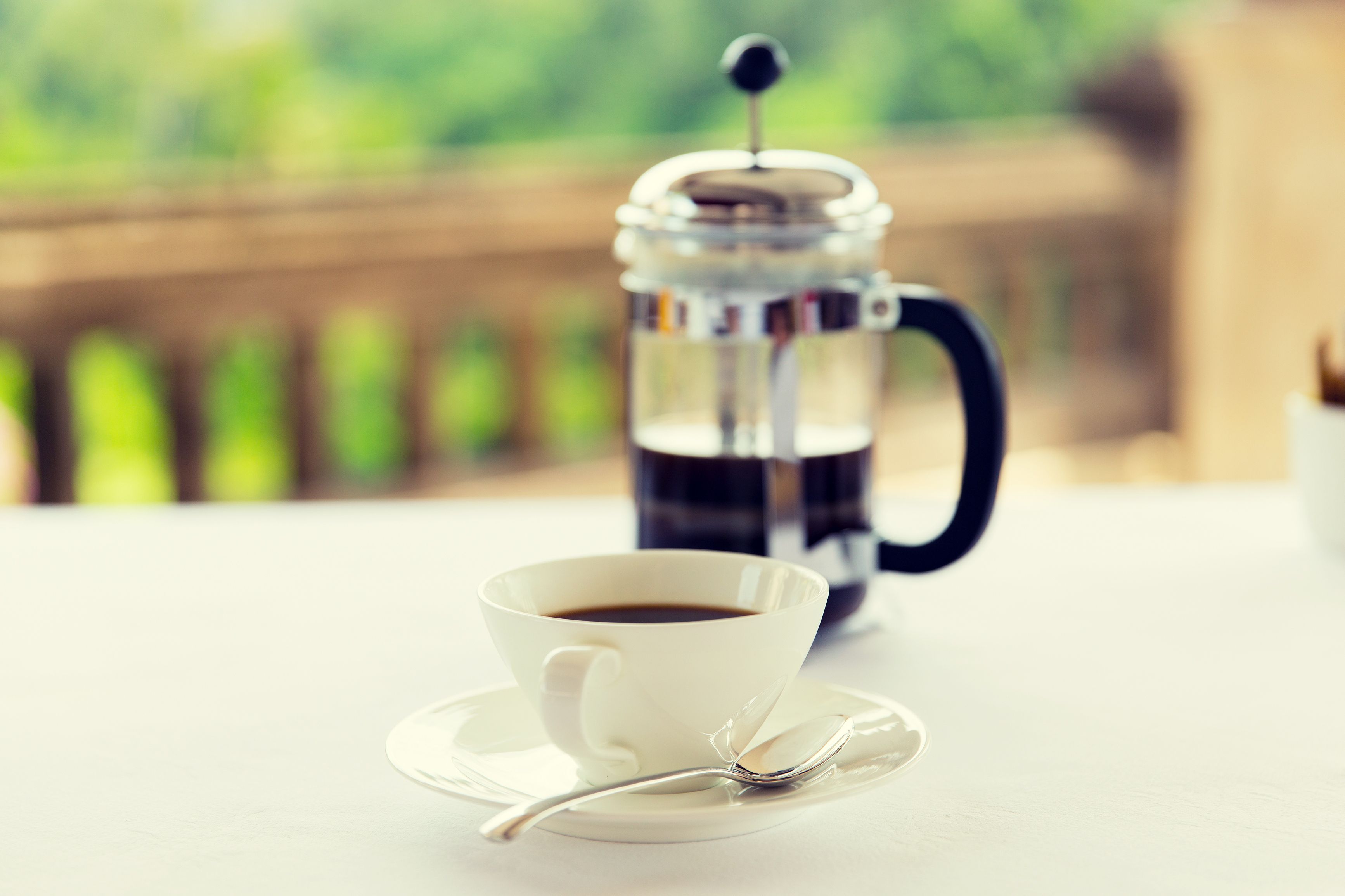 drinks, energetic, morning and caffeine concept - cup of black coffee and french press on table at restaurant