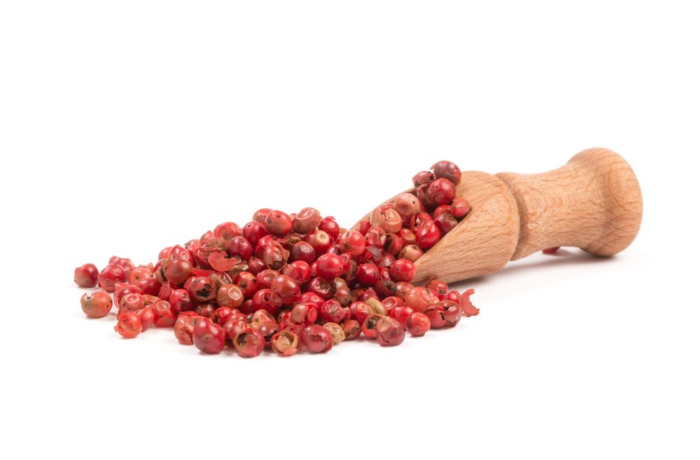 Pink pepper, Red peppercorns in a wooden spoon. Pink pepper, Red peppercorns in a wooden spoon.