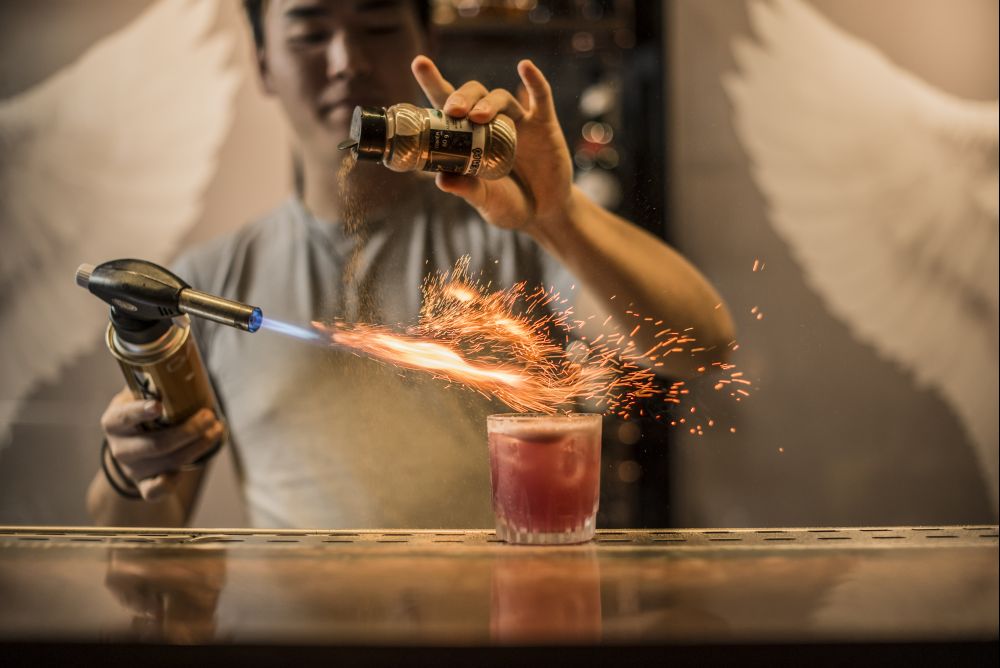 Elixer leva gin, xarope de vinho e especiarias, suco de limão siciliano e aquafaba e é finalizado com canela queimada. Foto: Munir Bucair Filho/Divulgação Elixer leva gin, xarope de vinho e especiarias, suco de limão siciliano e aquafaba e é finalizado com canela queimada. Foto: Munir Bucair Filho/Divulgação