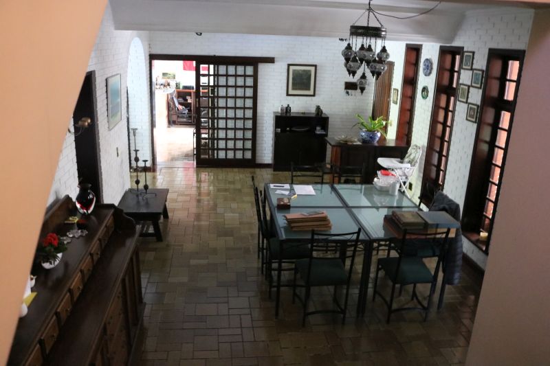 Nas salas, alguns dos destaques são as mesas de vidro, o jogo de mesa de jantar de Imbuia com dez cadeiras e dois aparadores, lustres e uma estante em módulos para montar conforme o espaço disponível. Nas salas, alguns dos destaques são as mesas de vidro, o jogo de mesa de jantar de Imbuia com dez cadeiras e dois aparadores, lustres e uma estante em módulos para montar conforme o espaço disponível.