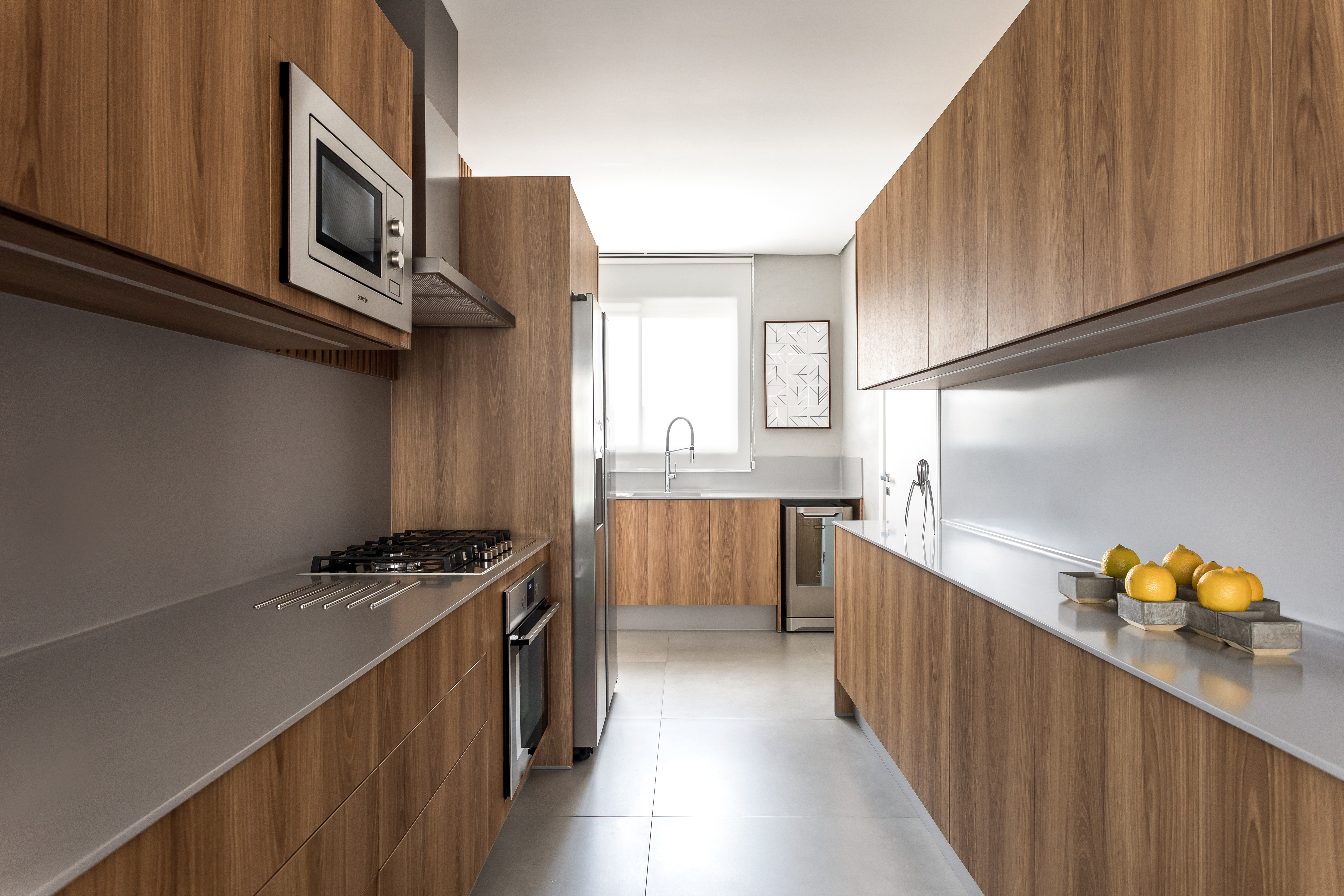 A cozinha, unida à área social, explora os tons de
madeira e Corian cinza, com móveis totalmente sem
puxadores, assim como no restante da casa. A cozinha, unida à área social, explora os tons de
madeira e Corian cinza, com móveis totalmente sem
puxadores, assim como no restante da casa.