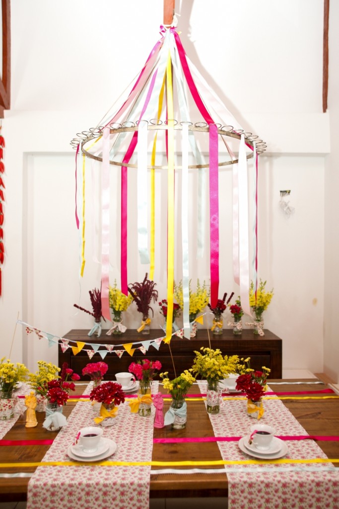 Em referência à dança das fitas, tradicional nas festas juninas, pode-se usar uma estrutura redonda presa ao teto, como um bambolê, por exemplo, e prender fitas de cetim de diversas cores, que ficarão suspensas sobre a mesa.
Foto: André Rodrigues / Gazeta do Povo Em referência à dança das fitas, tradicional nas festas juninas, pode-se usar uma estrutura redonda presa ao teto, como um bambolê, por exemplo, e prender fitas de cetim de diversas cores, que ficarão suspensas sobre a mesa.
Foto: André Rodrigues / Gazeta do Povo