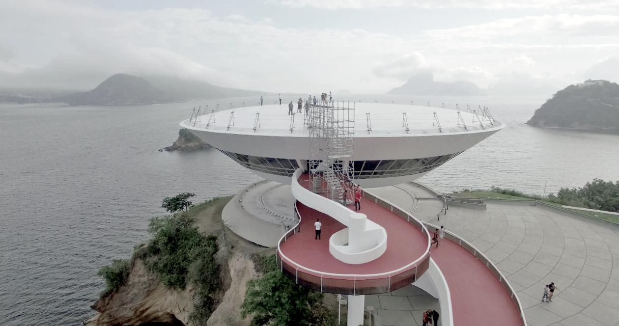 Instalação da Grua no teto do MAC de Niterói propôs aos visitantes encarar o prédio de Niemeyer sob nova perspectiva. Foto: Tui Lana/divulgação Instalação da Grua no teto do MAC de Niterói propôs aos visitantes encarar o prédio de Niemeyer sob nova perspectiva. Foto: Tui Lana/divulgação