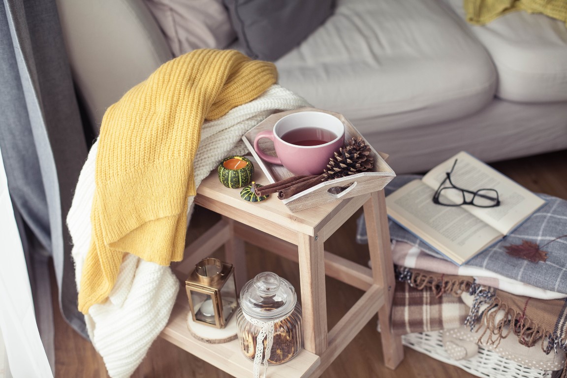 Knitted, warm sweaters, a cup of hot tea, autumn decor, a book, a pumpkin on a wooden chair. Cozy, autumn decor. Autumn interior, sofa. Autumn. Winter. Knitted, warm sweaters, a cup of hot tea, autumn decor, a book, a pumpkin on a wooden chair. Cozy, autumn decor. Autumn interior, sofa. Autumn. Winter.