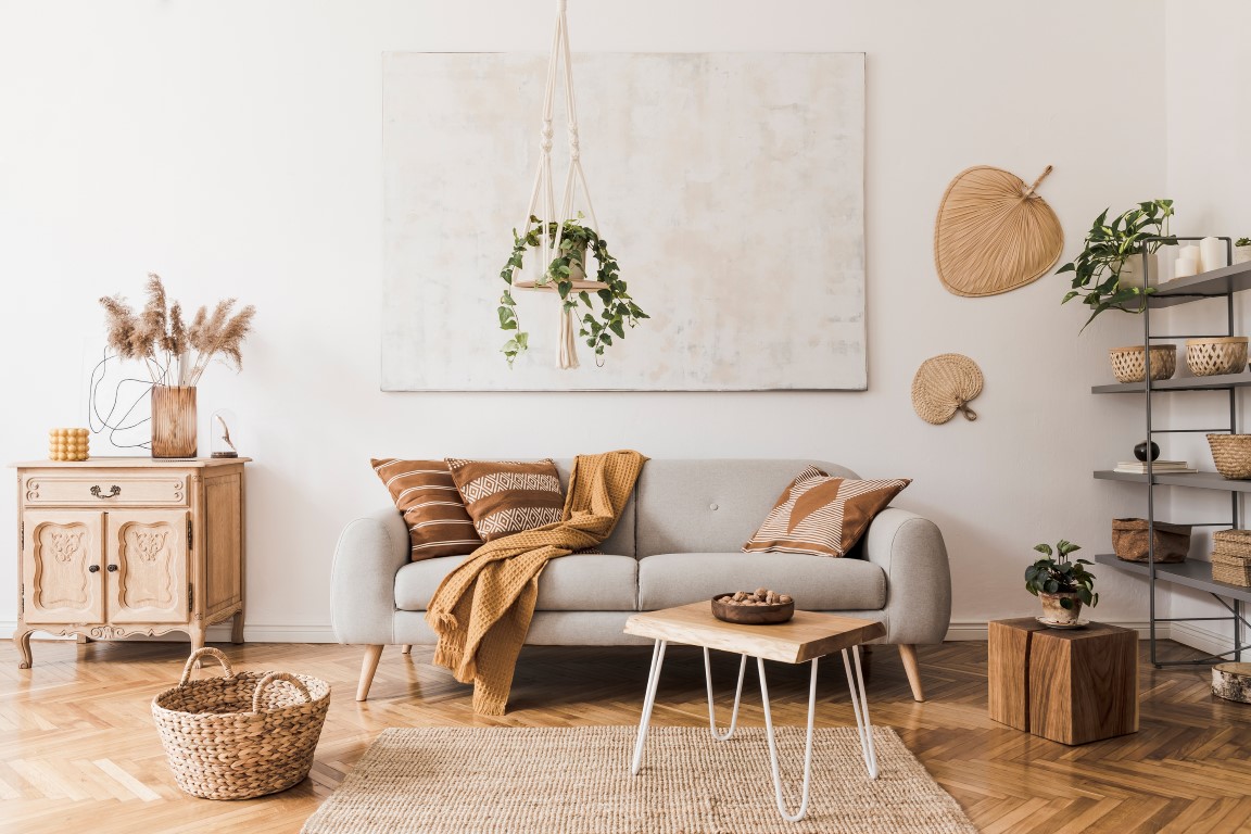 The stylish boho compostion at living room interior with design gray sofa, wooden coffee table, commode and elegant personal accessories. Honey yellow pillow and plaid. Cozy apartment. Home decor The stylish boho compostion at living room interior with design gray sofa, wooden coffee table, commode and elegant personal accessories. Honey yellow pillow and plaid. Cozy apartment. Home decor