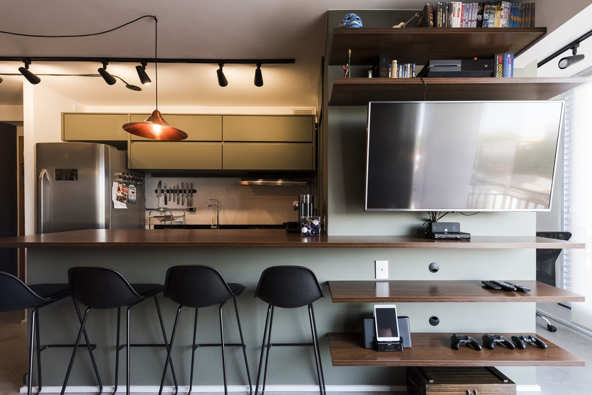 Bancada se abre para se transformar em mesa de jantar, mas segue até a sala como apoio para equipamentos. Foto: Rafael Roncato/Divulgação Bancada se abre para se transformar em mesa de jantar, mas segue até a sala como apoio para equipamentos. Foto: Rafael Roncato/Divulgação